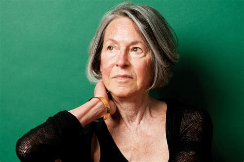photo of louise gluck. Woman wearing a black top with a green background
