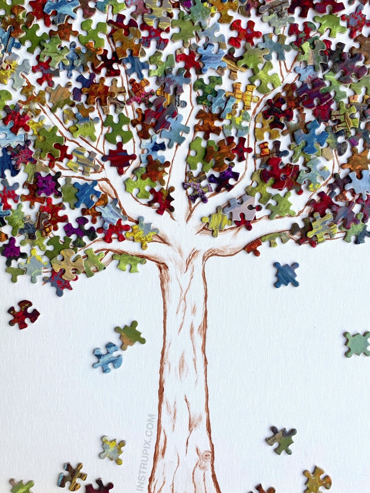 A canvas with multicolored puzzle pieces used to resemble leaves on a tree