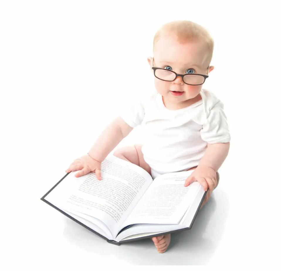 Baby holding book while wearing glasses