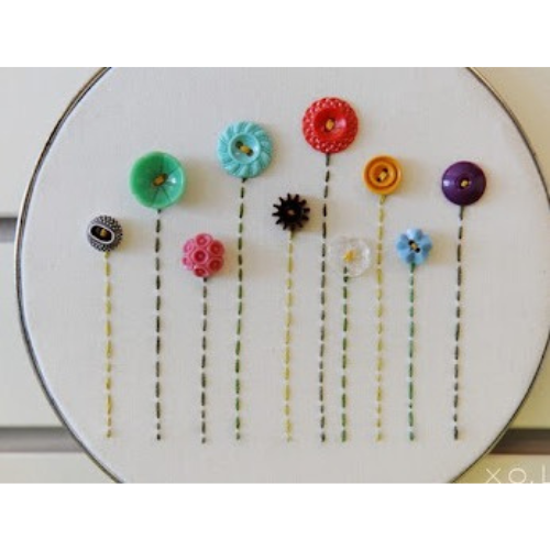 An embroidery hoop with varying shades of buttons and thread to resemble spring flowers