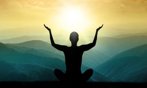 Stock photo of a person meditating on top of a mountain