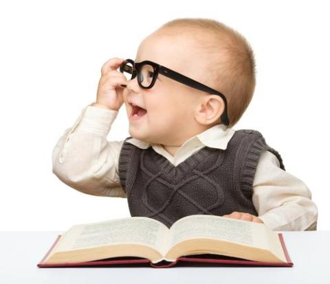 A baby with very smart glasses reads a chapter book.