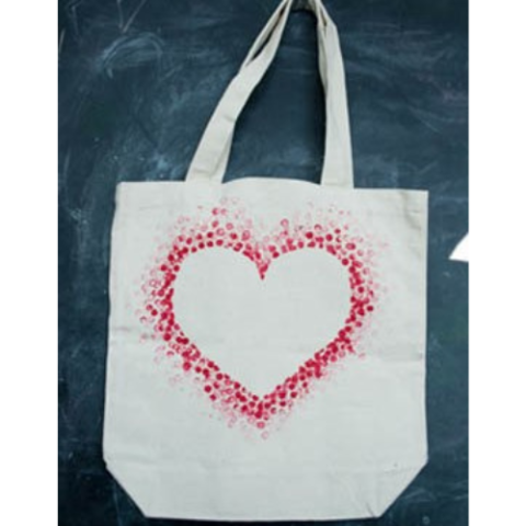 A white canvas tote bag with red dots arranged to form the outline of a heart