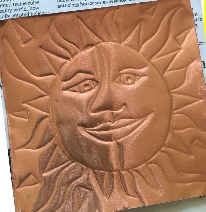 Copper foil with a smiling sun embossed in the center