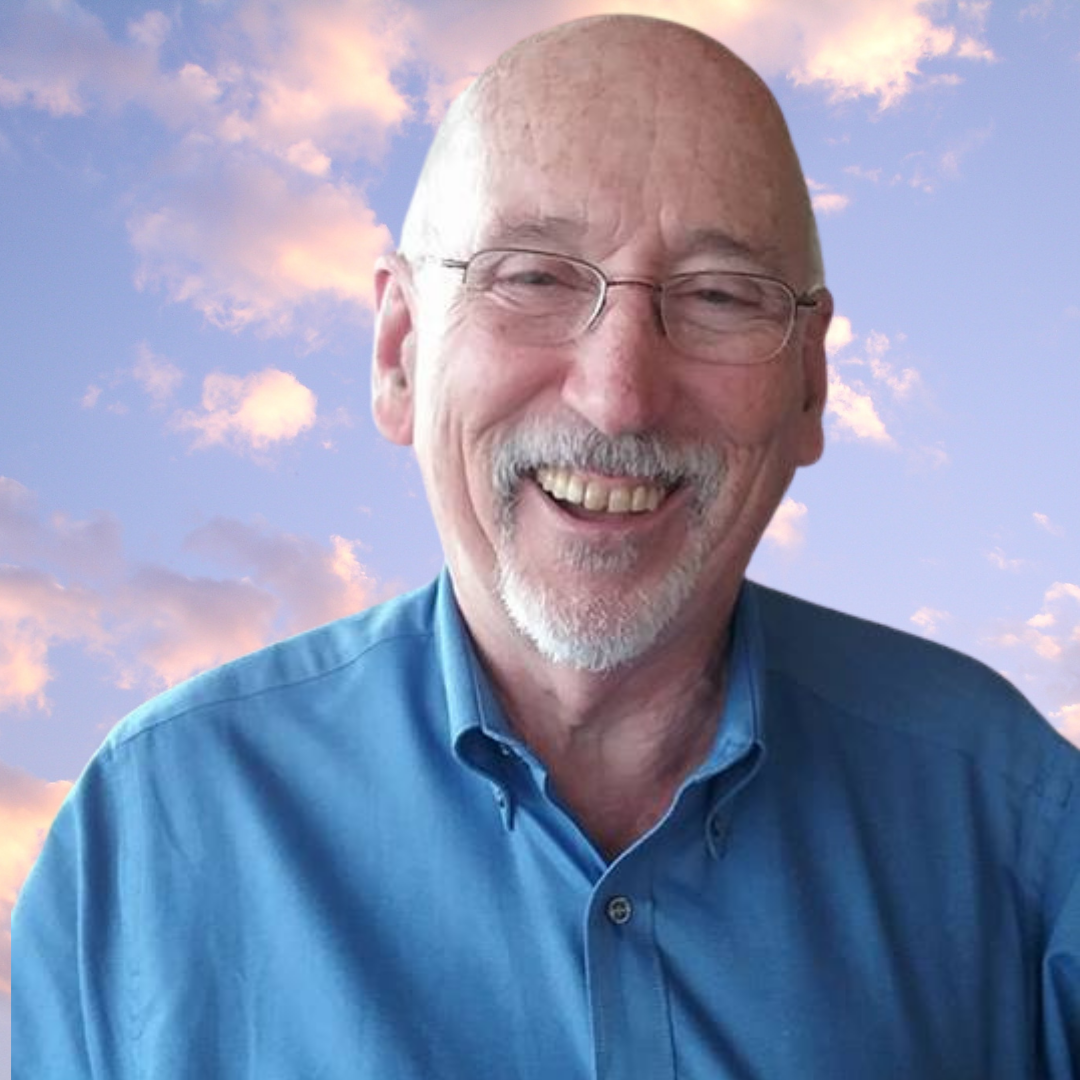 Portrait photo of a man in a blue shirt in front of a blue sky with clouds