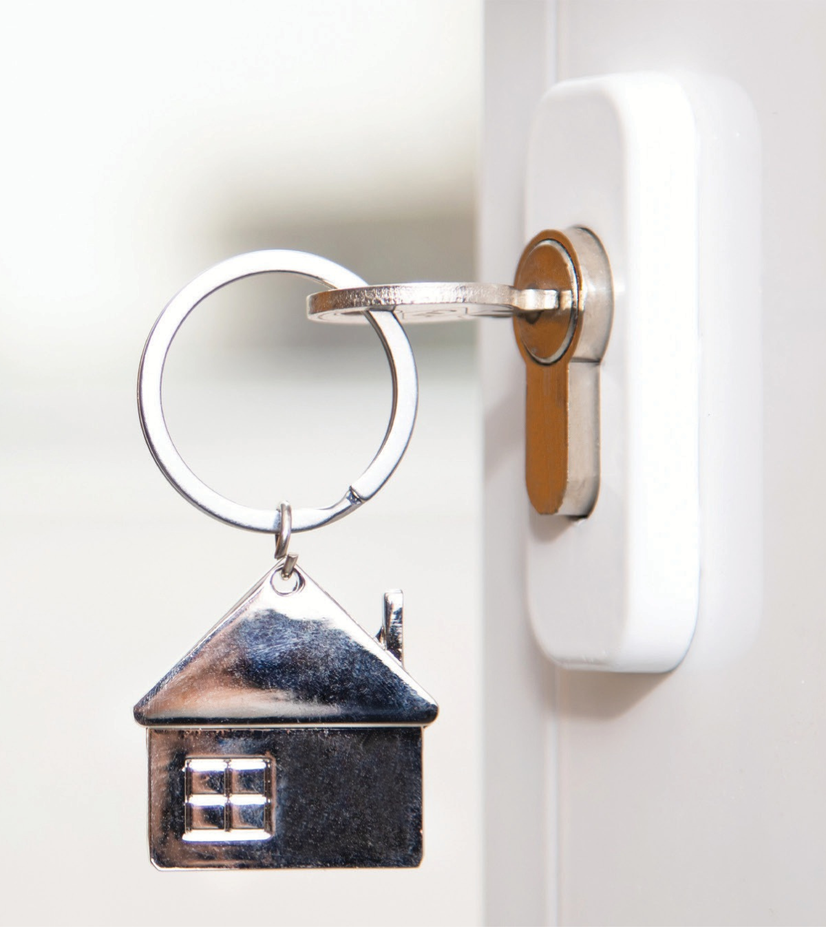 A key inserted into a lock. The keychain is in the shape of a house.